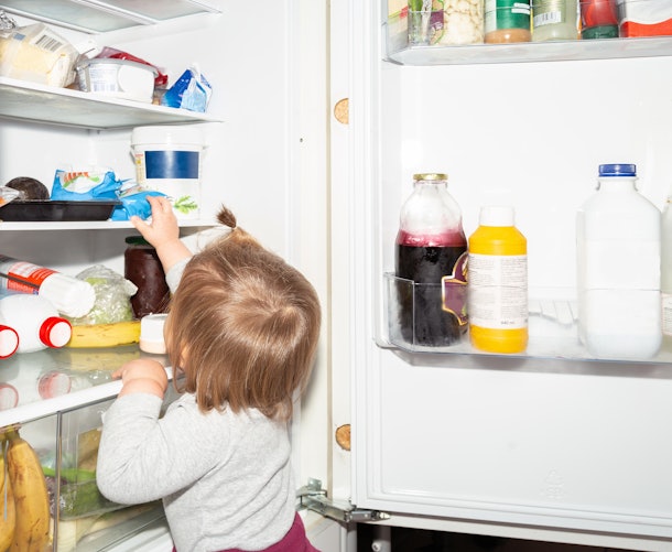 Little girl against a fridge. Cute little girl a year